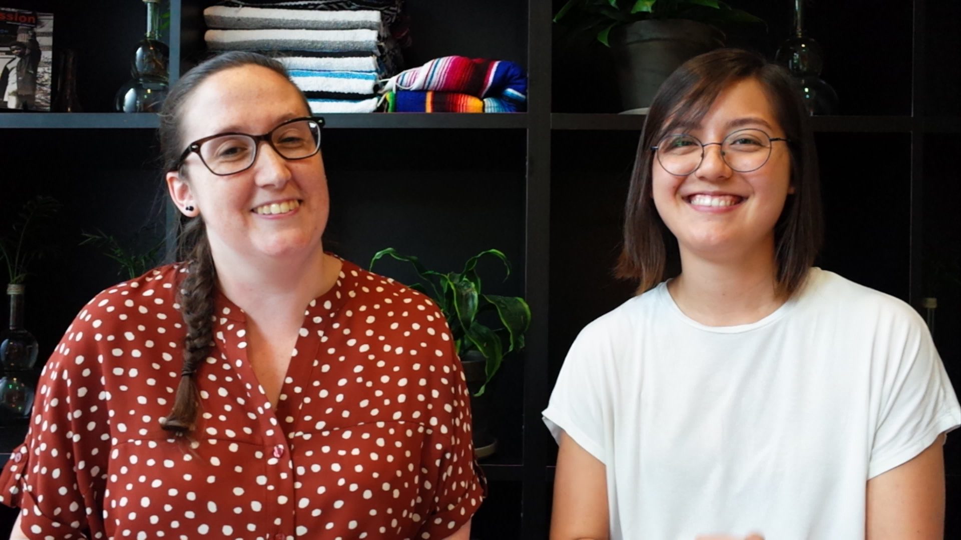two ladies smile and pose in front of a bookcase